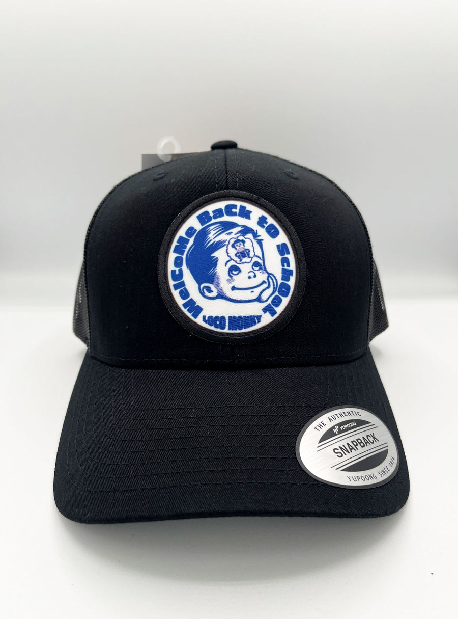 Gorra trucker Welcome Back de Loco Monky en negro, con parche de niño y mensaje "Welcome Back to School".