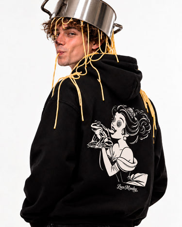 Sudadera negra unisex con diseño de princesa y rana en la parte posterior, modelo con pelo rizado y olla en la cabeza.