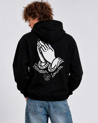 Sudadera negra con capucha, diseño de manos en oración y texto 'Bendita Locura' en la espalda.