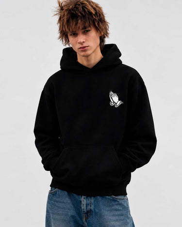 Sudadera unisex negra con capucha y diseño de manos en el pecho, modelo masculino con cabello desordenado.