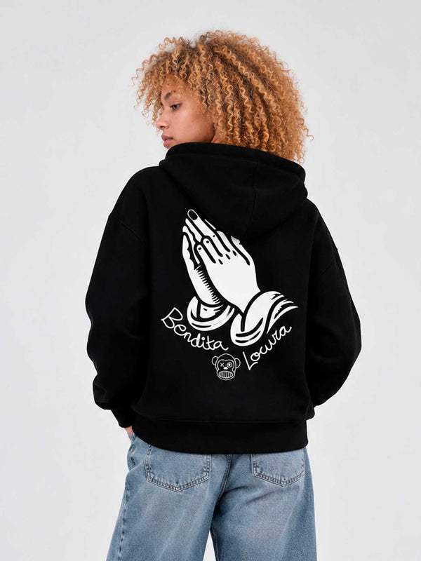 Sudadera negra con capucha, diseño de manos en oración y texto 'Bendita Locura' en la parte posterior.