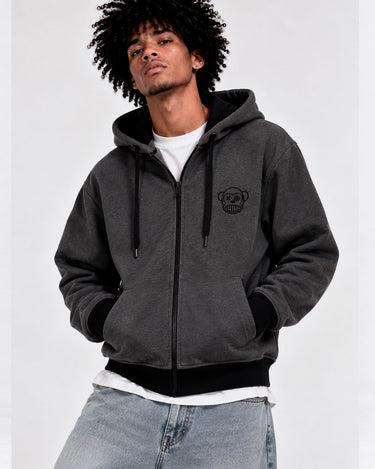 Sudadera con cremallera en gris oscuro, con capucha y logo de Loco Monky en el pecho, modelo masculino posando.