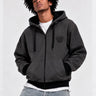 Sudadera con cremallera en gris oscuro, con capucha y logo de Loco Monky en el pecho, modelo masculino posando.