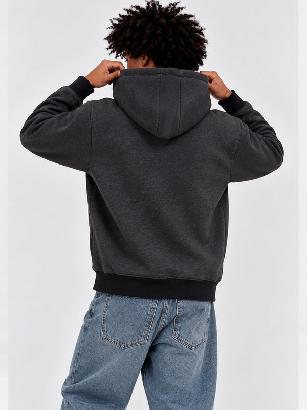 Sudadera con capucha gris oscuro, vista trasera, con puños y cintura en negro, combinada con jeans claros.
