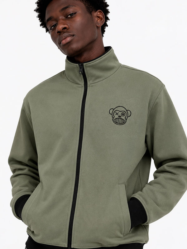 Chaqueta sin capucha en color oliva con logo de mono en el pecho, cierre frontal y puños negros.