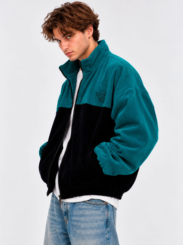 Chaqueta de pana oversize en negro y azul océano, con cierre y cuello alto, estilo unisex.