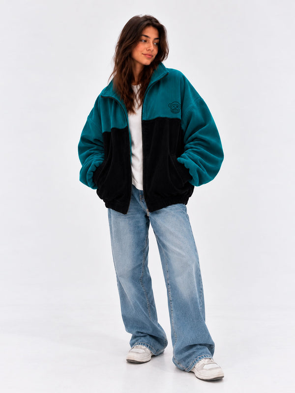 Chaqueta de pana oversize unisex en negro y azul océano, con logo en el pecho y pantalones de mezclilla claros.