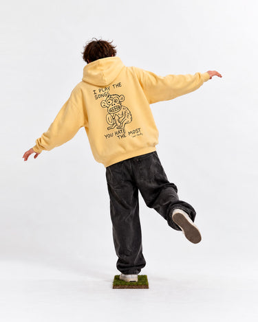 Sudadera unisex amarilla suave con diseño de un mono en la parte trasera, pantalones oscuros, persona de espaldas.