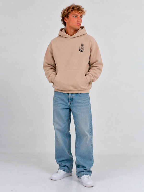 Sudadera unisex color arena con capucha, logo de Loco Monky en el pecho, pantalones de mezclilla claros.