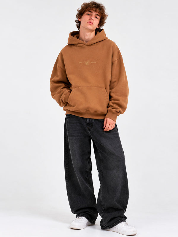Sudadera oversize color marrón con capucha, logo de Loco Monky en el pecho, pantalones anchos y zapatillas blancas.