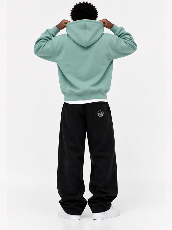 Pantalón oversize negro con logo en la parte trasera, combinado con sudadera verde claro, vista trasera.