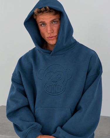Sudadera unisex de color azul profundo con capucha y diseño de mono en relieve en el pecho.