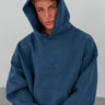 Sudadera unisex de color azul profundo con capucha y diseño de mono en relieve en el pecho.