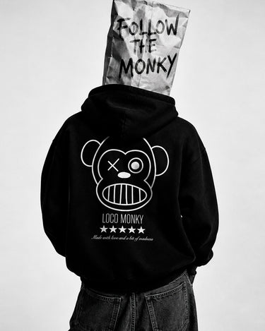 Sudadera negra con diseño de mono y texto 'LOCO MONKY' en la parte trasera, persona con bolsa en la cabeza.
