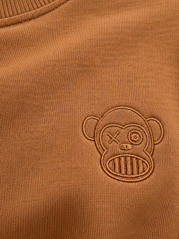 Sudadera color caramelo con bordado de un mono en el pecho.