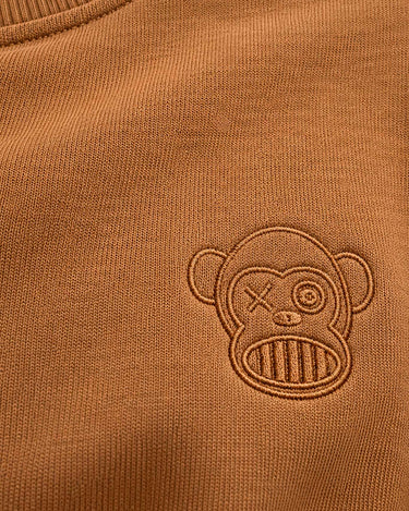 Sudadera color caramelo con bordado de un mono en el pecho.