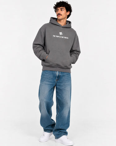 Sudadera unisex de color gris profundo con capucha y texto blanco en el pecho, pantalones vaqueros azules.